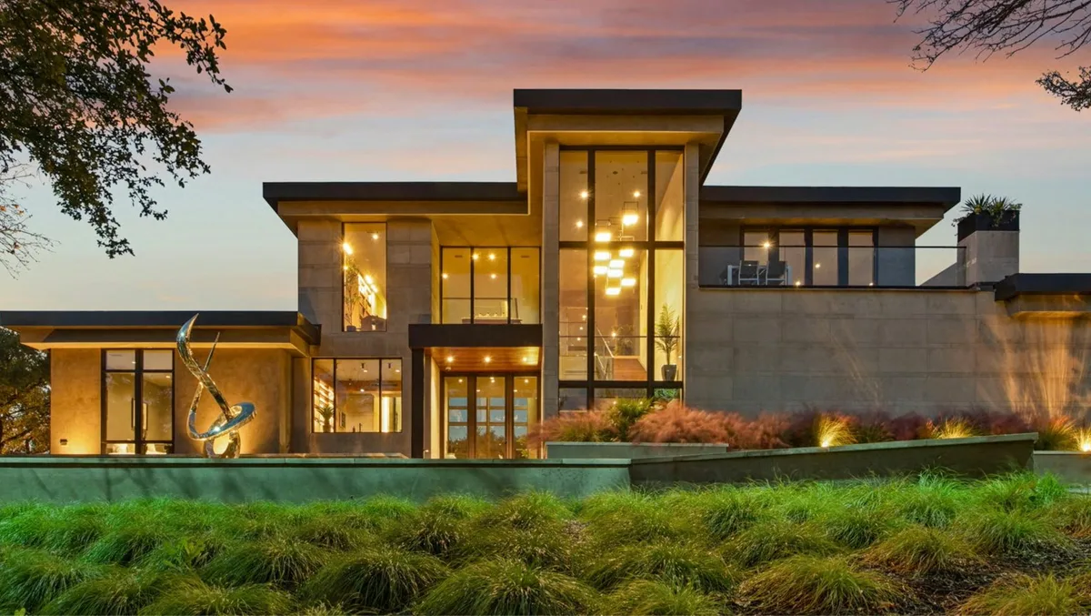 Modern home with tall lit windows at dusk in Great Falls, Virginia